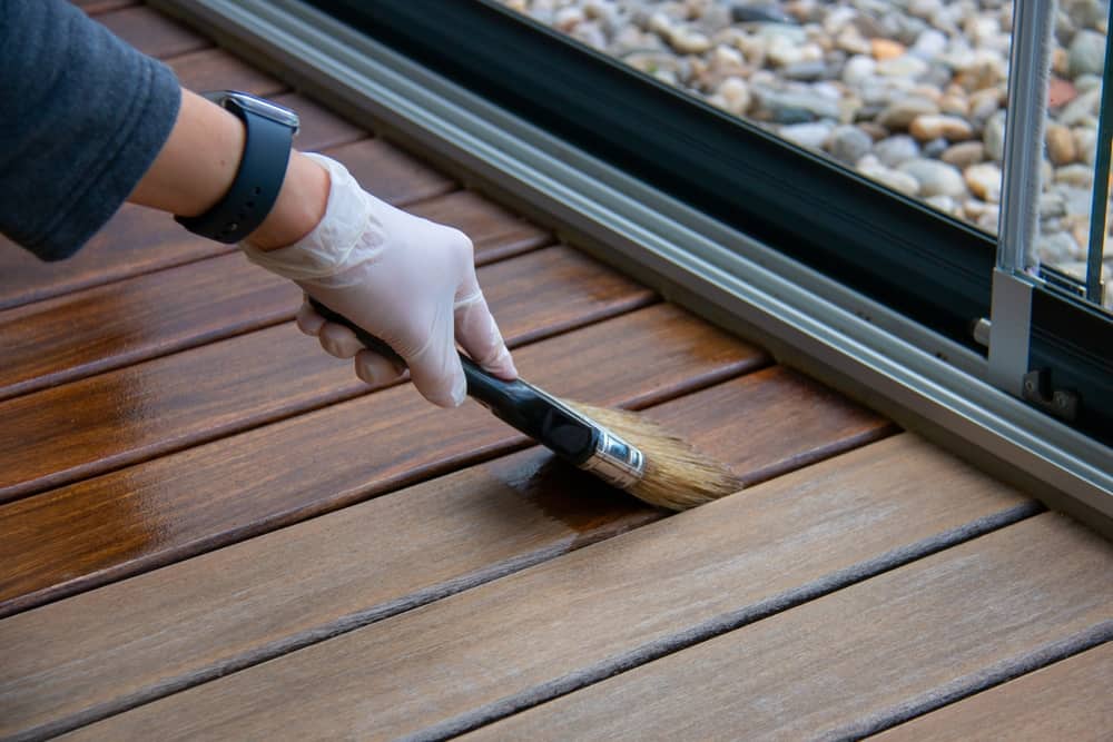 deck,staining,,worker,applying,deck,oil,on,decking,boards,with