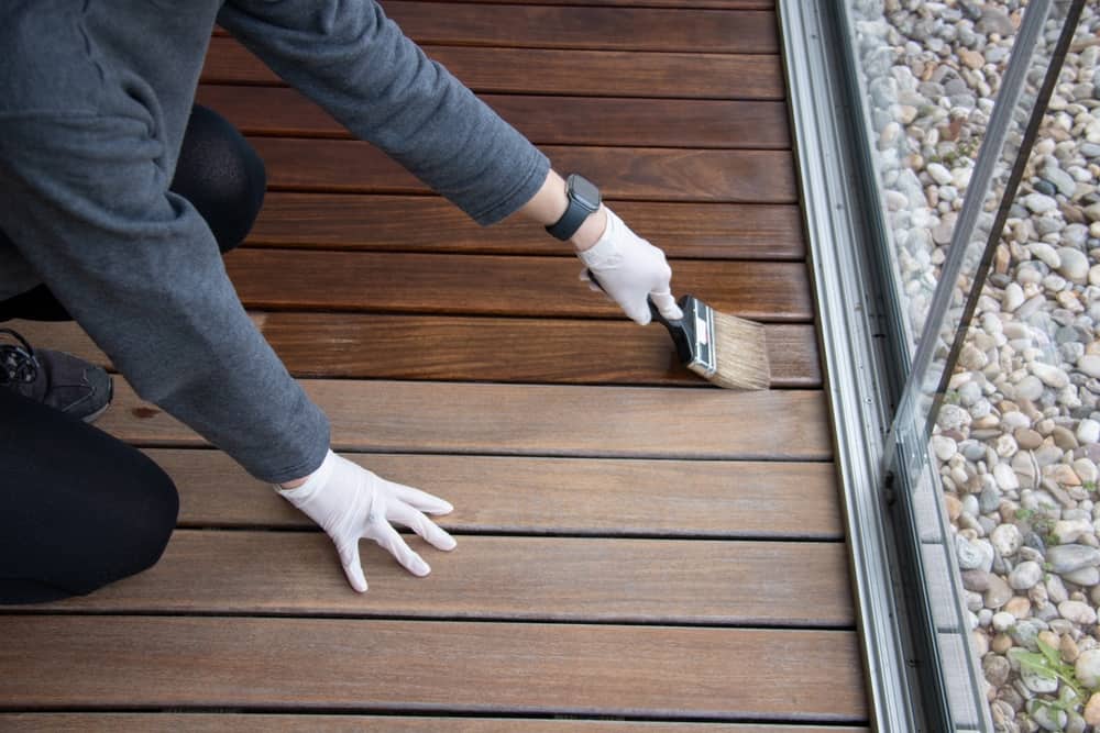 worker,refinishing,wood,,hand,painting,wooden,deck,floor,with,wood